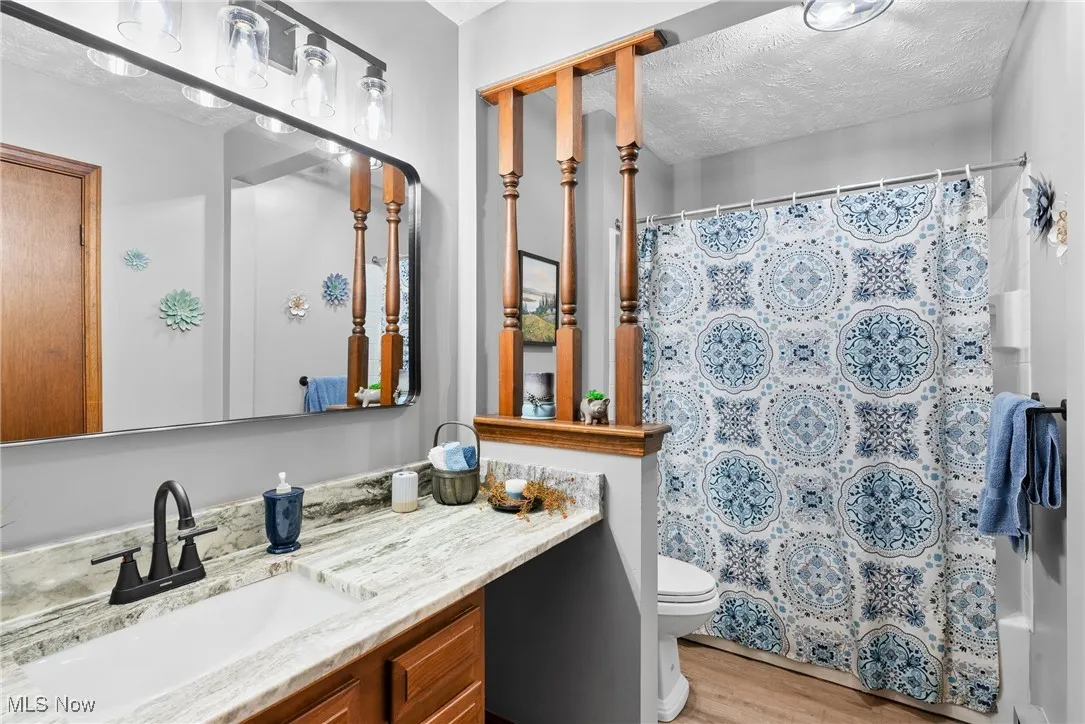Bathroom featuring a textured ceiling, light wood finished floors, and vanity