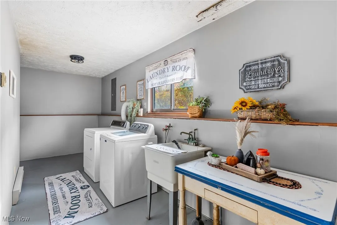 Laundry area with concrete floors, a textured ceiling, washing machine and dryer, and baseboard heating