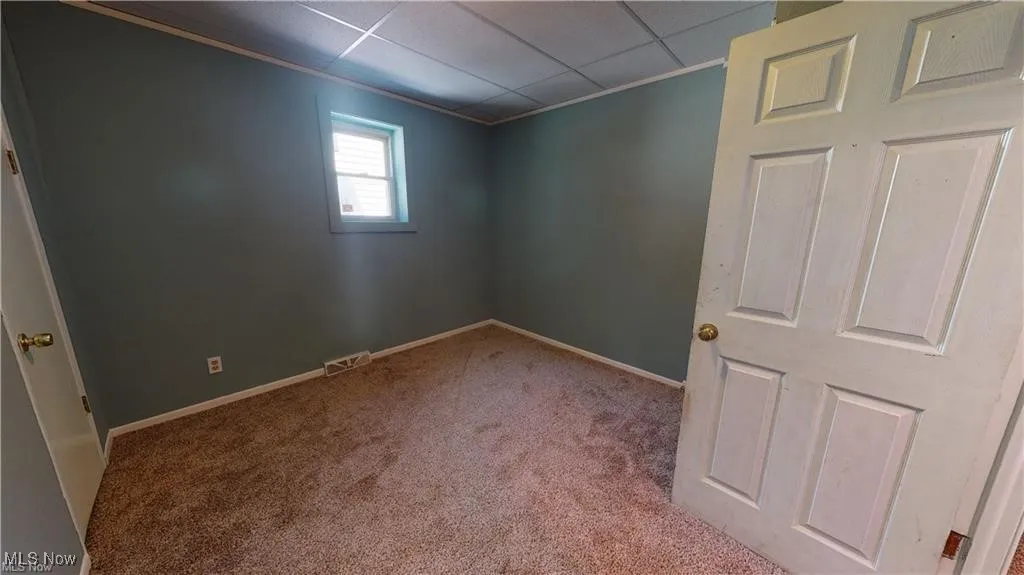 Unfurnished room featuring carpet flooring, a paneled ceiling, and crown molding