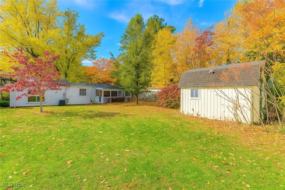 View of green lawn with a storage unit and a sunroom