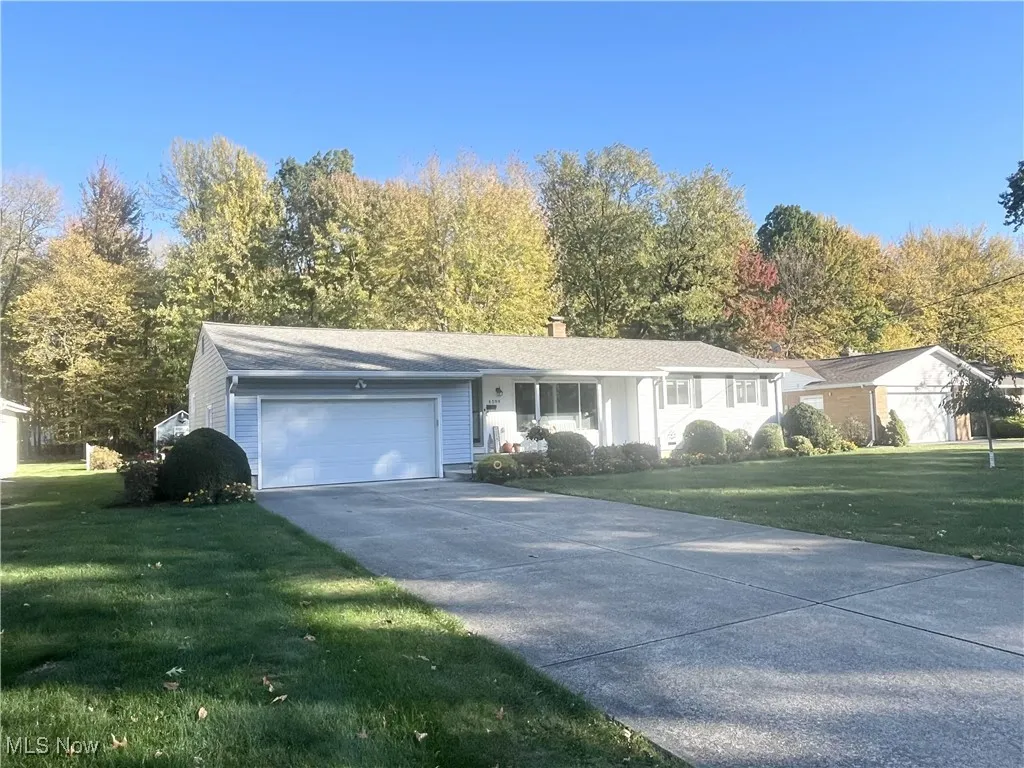 Single story home featuring a front yard, an attached garage, a chimney, and concrete driveway
