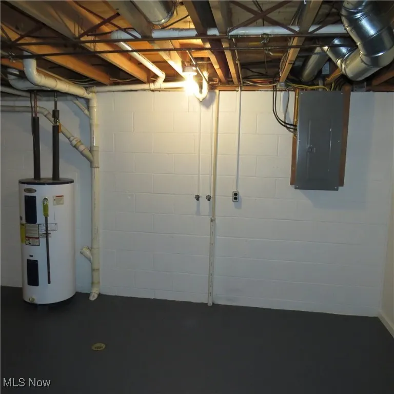Unfinished below grade area featuring electric panel and water heater