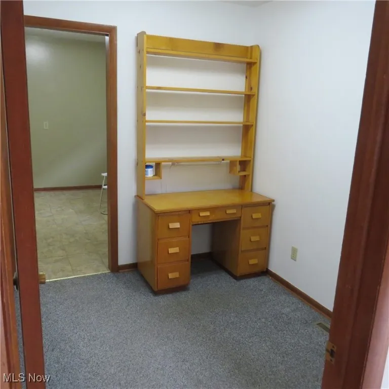 Unfurnished office featuring dark carpet and baseboards