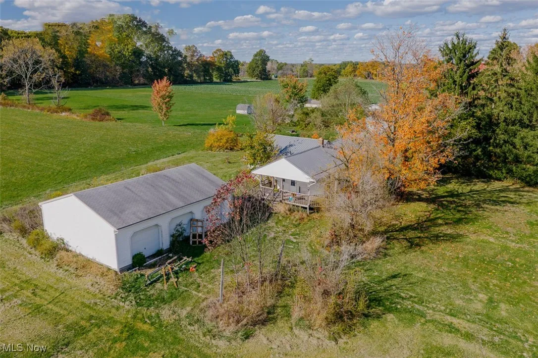 Aerial view of garage featuring a tree filled landscape