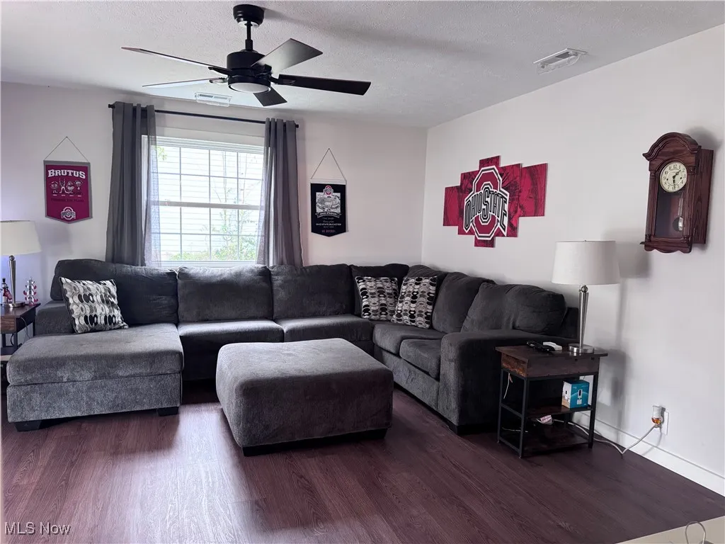 Living room featuring wood finished floors, a textured ceiling, and ceiling fan