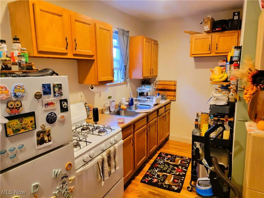 Kitchen featuring white appliances, light wood-style flooring, light countertops, and brown cabinetry