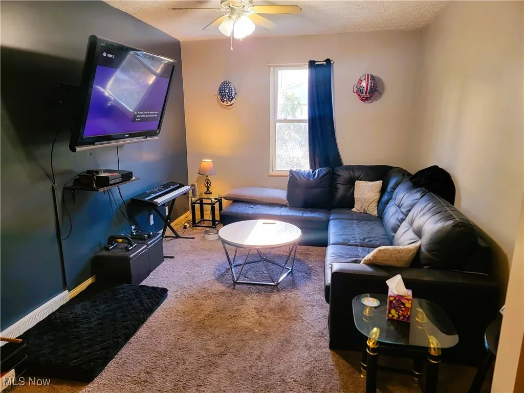 Carpeted living area featuring a textured ceiling and a ceiling fan