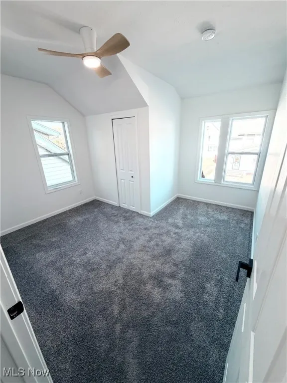  bedroom featuring dark colored carpet, a ceiling fan, multiple windows, and a closet