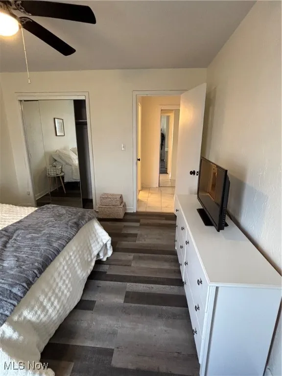 Bedroom with a closet, dark wood finished floors, and a ceiling fan