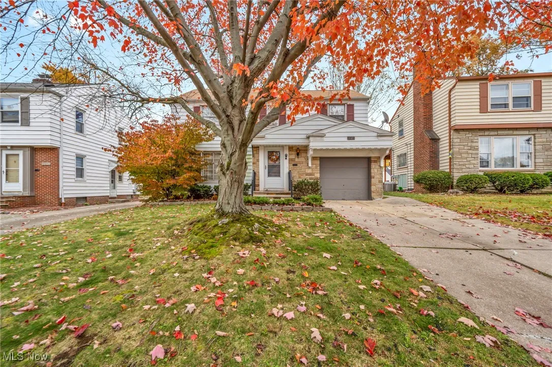 View of front of home with a front lawn, driveway, stone siding, and an attached garage