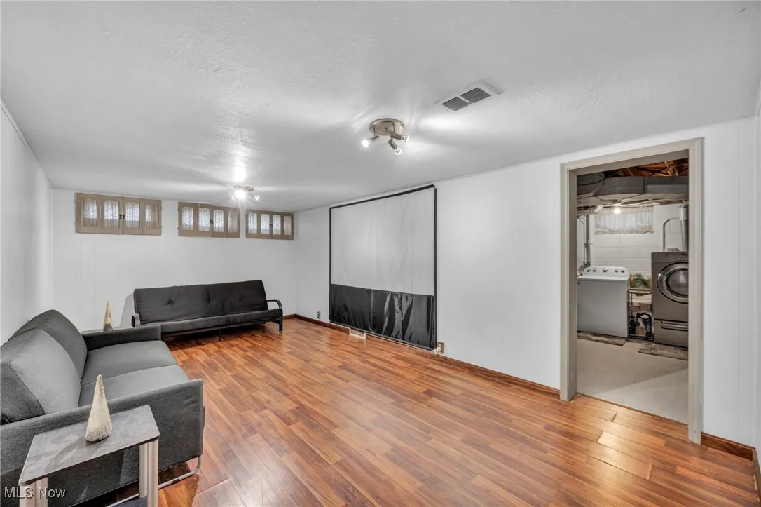 Living area featuring wood finished floors, a textured ceiling, and washer / dryer