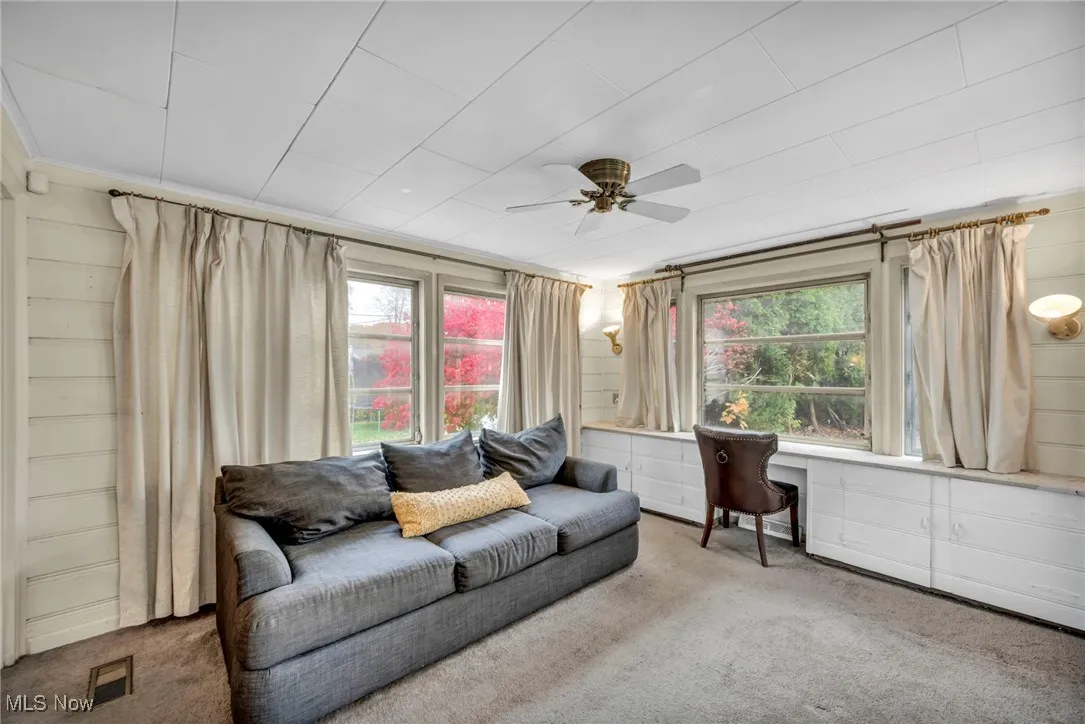 Enclosed porch featuring carpet flooring, ceiling fan, and a desk