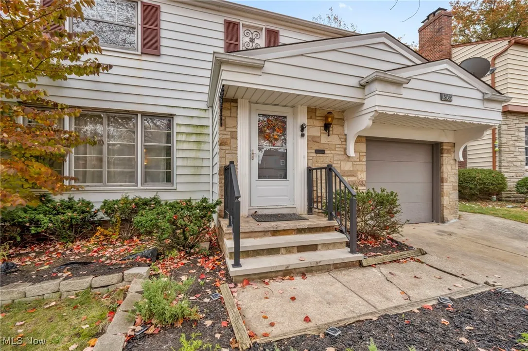View of exterior entry featuring stone siding, concrete driveway, an attached garage, and a chimney
