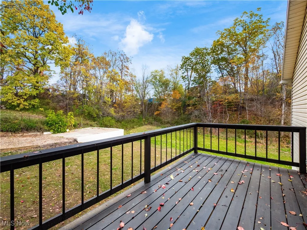 Wooden terrace featuring a yard and view of wooded area