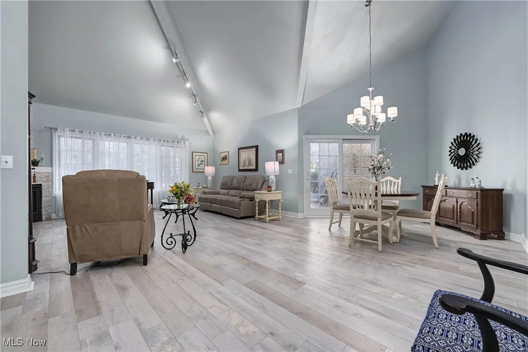 Living area with high vaulted ceiling, a chandelier, light wood-style flooring, and track lighting
