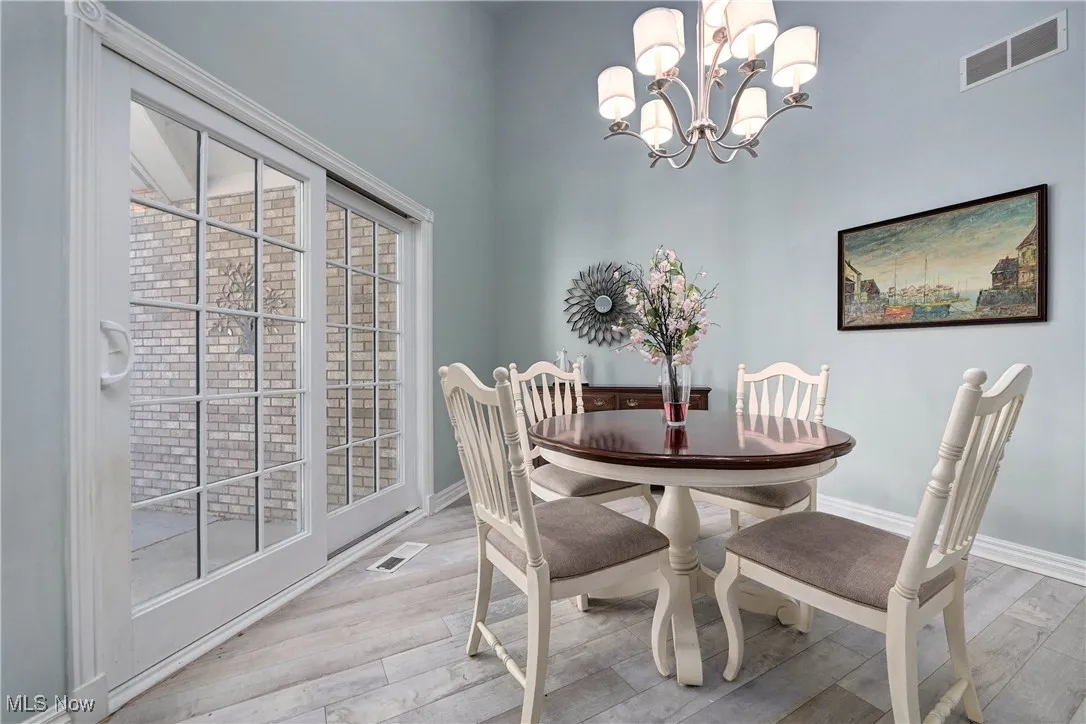 Dining room featuring light wood-style flooring, a chandelier, and a high ceiling