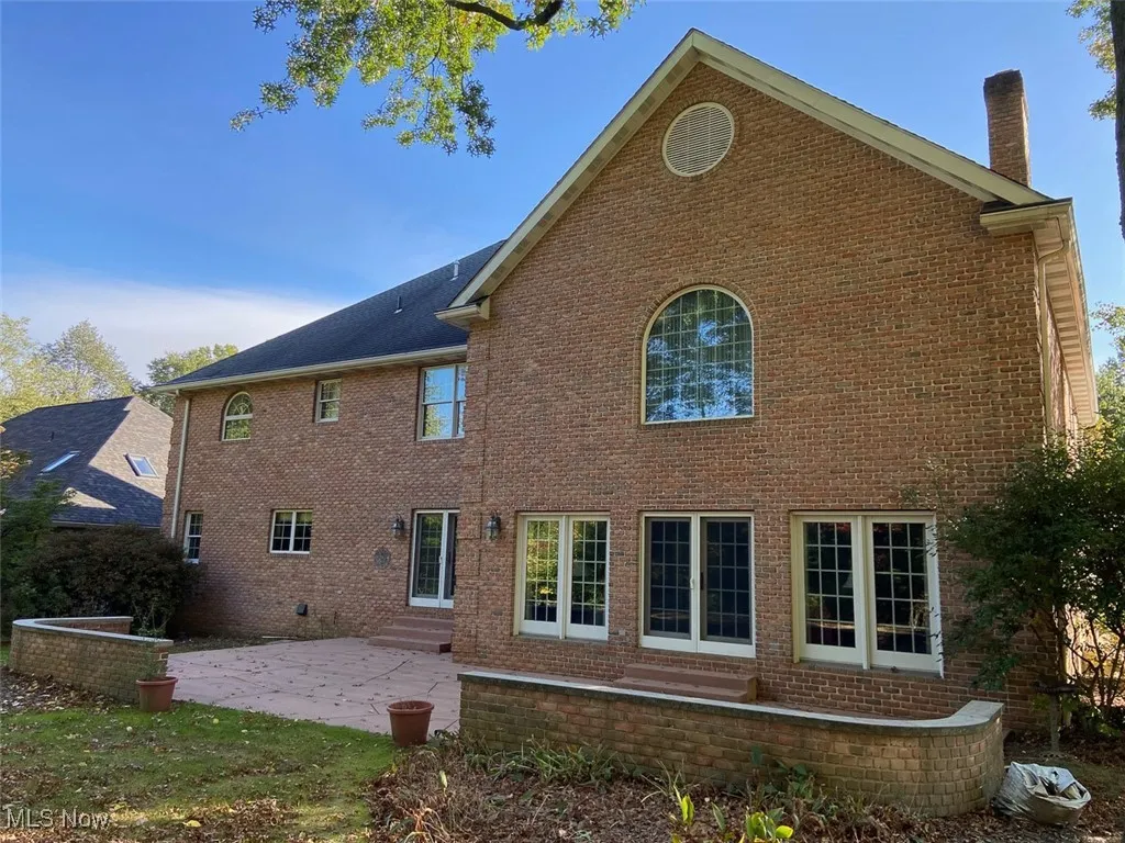Back of house with a patio area, brick siding, a chimney, and entry steps