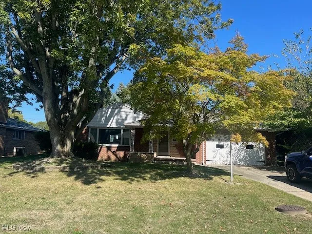 View of front of house with a front yard, brick siding, and driveway