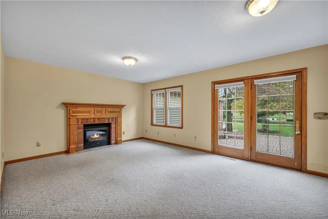 Unfurnished living room with a fireplace, light colored carpet, and a textured ceiling