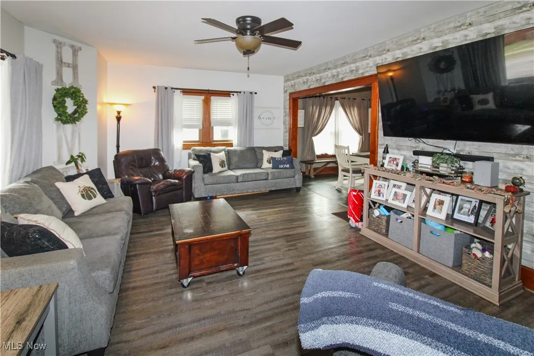 Living area featuring plenty of natural light, dark wood finished floors, and a ceiling fan