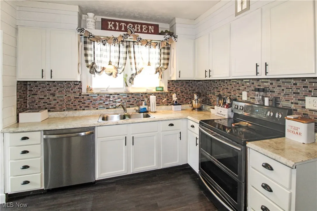 Kitchen featuring double oven range, dishwasher, light countertops, white cabinets, and decorative backsplash