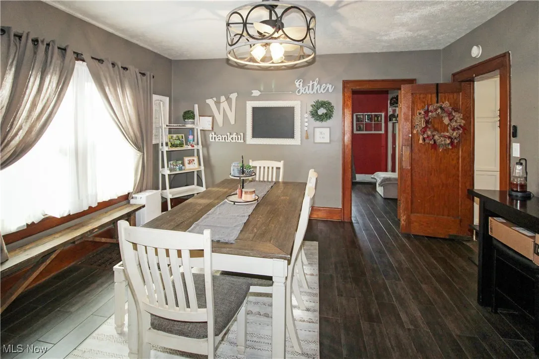 Dining area with dark wood-style floors, a chandelier, and a textured ceiling