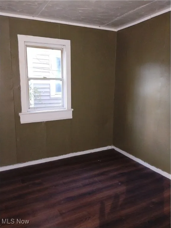 Empty room featuring dark wood-style floors and baseboards