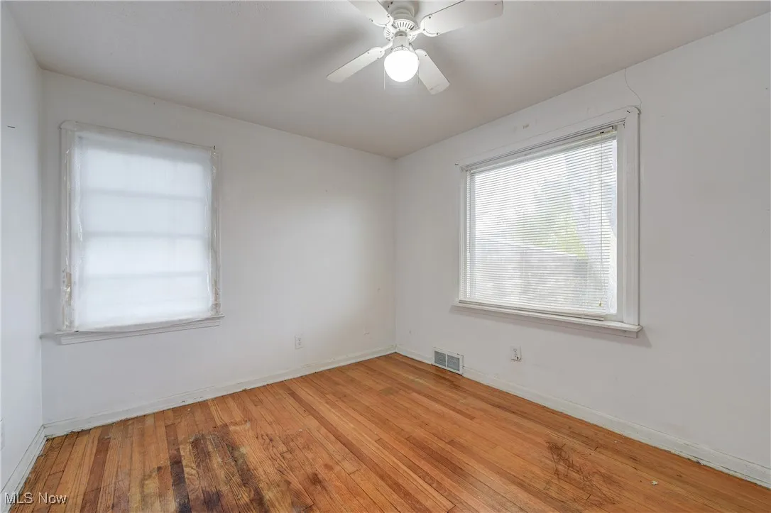 Unfurnished room with wood-type flooring, plenty of natural light, and a ceiling fan