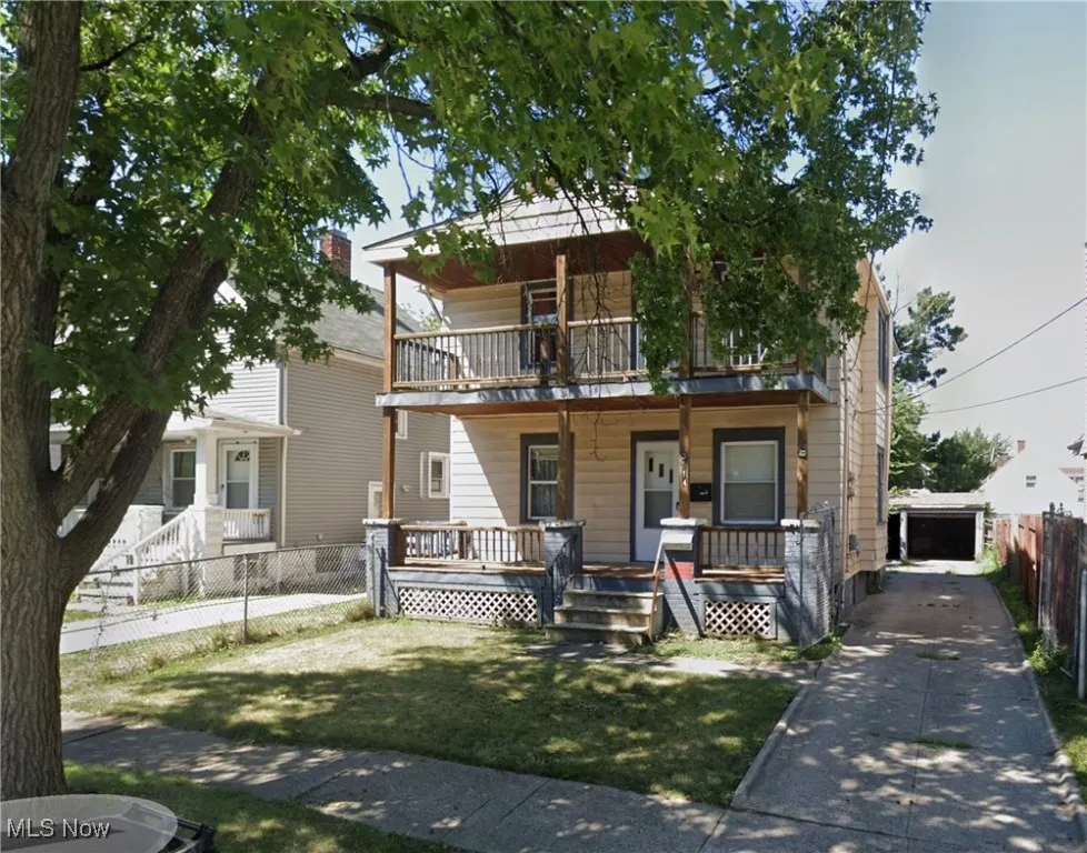 View of front of home with a porch, a garage, a balcony, and an outdoor structure