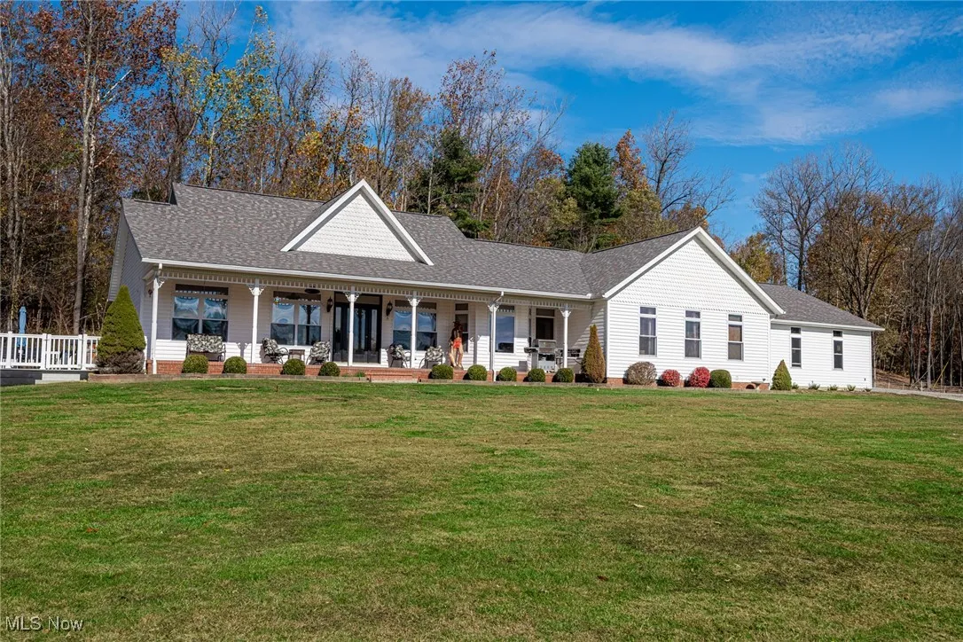 View of front of property featuring roof with shingles, a porch, and a front lawn