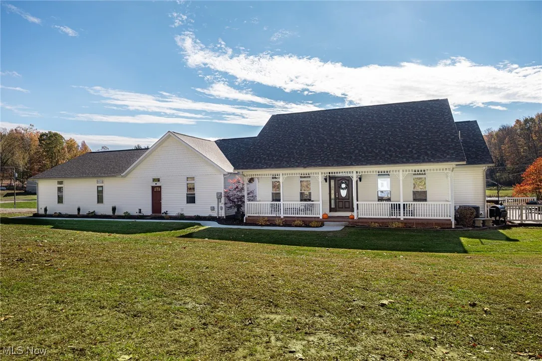 View of front of home with covered porch, a shingled roof, and a front lawn