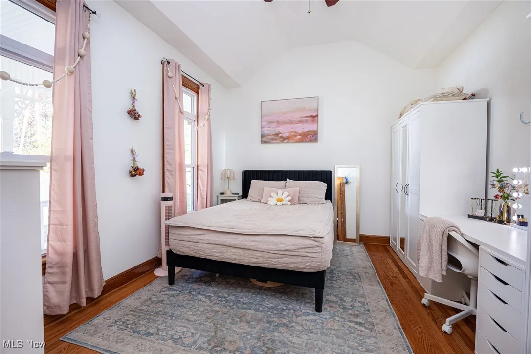 Bedroom featuring lofted ceiling, wood finished floors, ceiling fan, and a desk