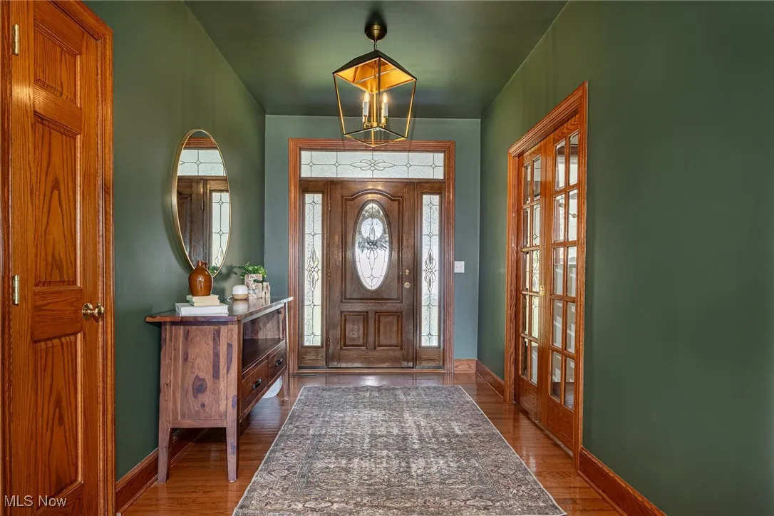 Foyer with wood finished floors, french doors, and a chandelier