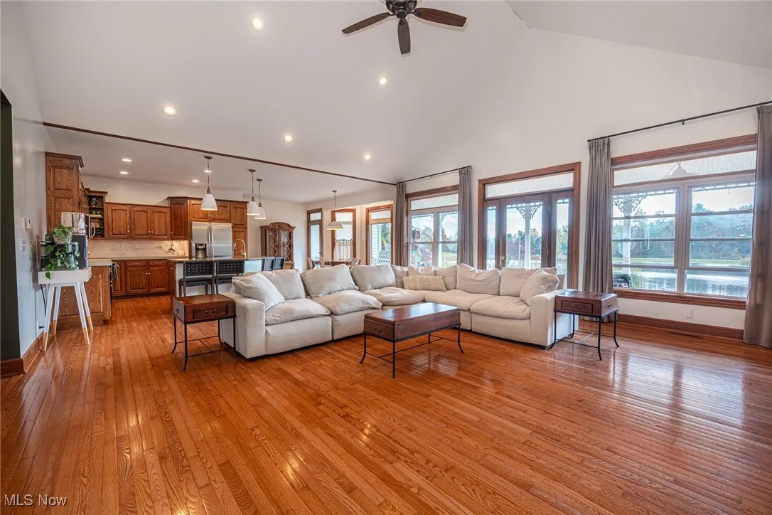 Living area featuring high vaulted ceiling, light wood-type flooring, recessed lighting, and ceiling fan