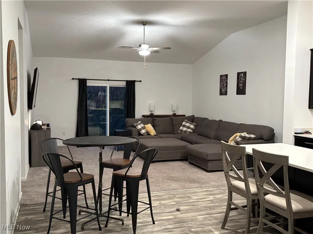 Living room featuring light wood-type flooring, ceiling fan, and lofted ceiling
