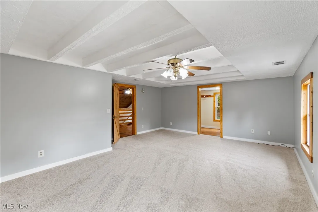 Empty room featuring light carpet, ceiling fan, and a textured ceiling