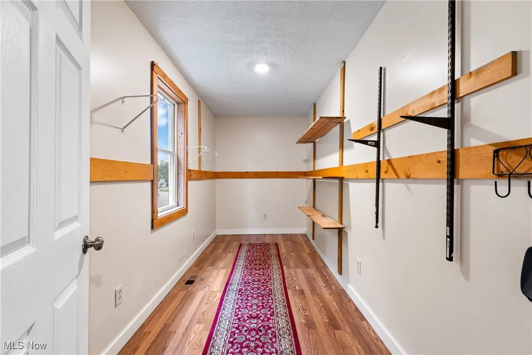 Corridor with light wood-style floors and a textured ceiling
