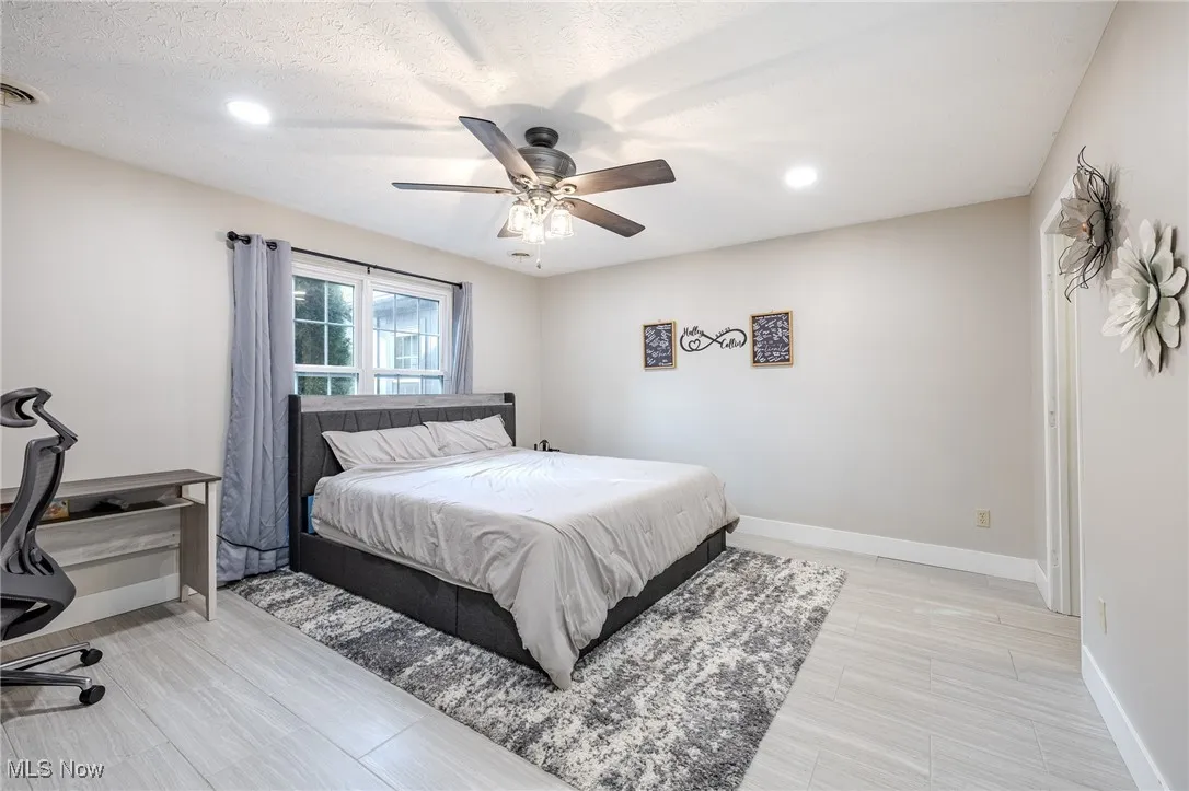 Bedroom with a ceiling fan, recessed lighting, light wood-type flooring, an office area, and a textured ceiling