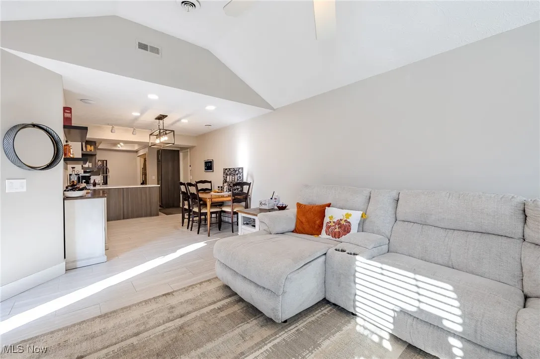 Living area featuring vaulted ceiling, a ceiling fan, light wood-style flooring, and recessed lighting