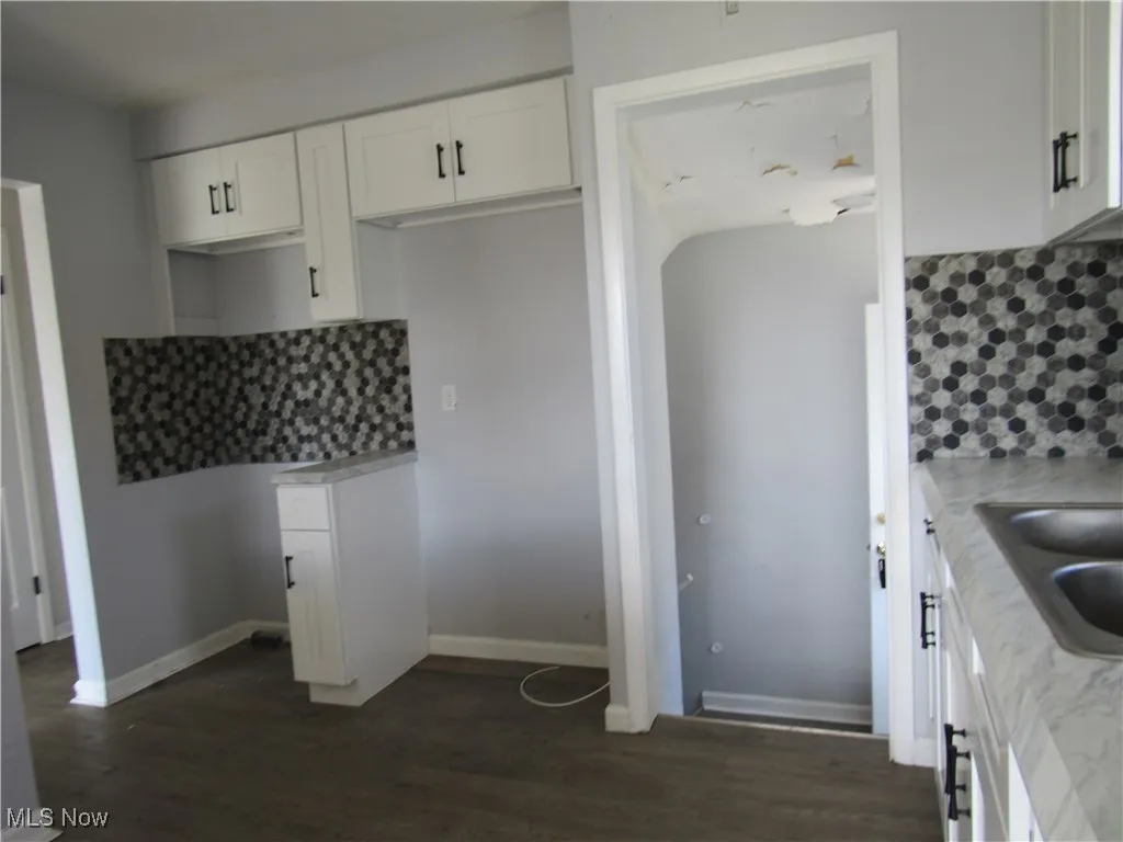 Kitchen with backsplash, white cabinets, and light countertops