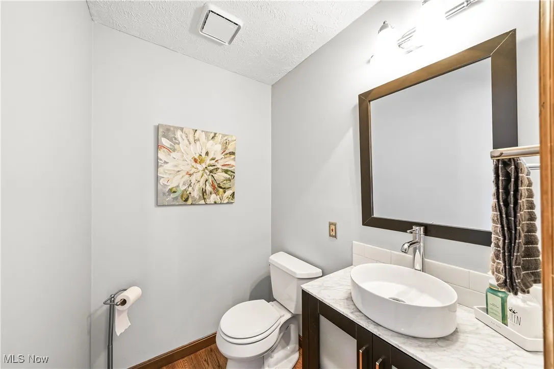 Bathroom featuring a textured ceiling, vanity, and wood finished floors