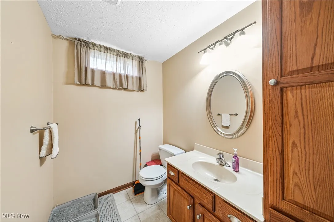 Bathroom with vanity, light tile patterned floors, and a textured ceiling