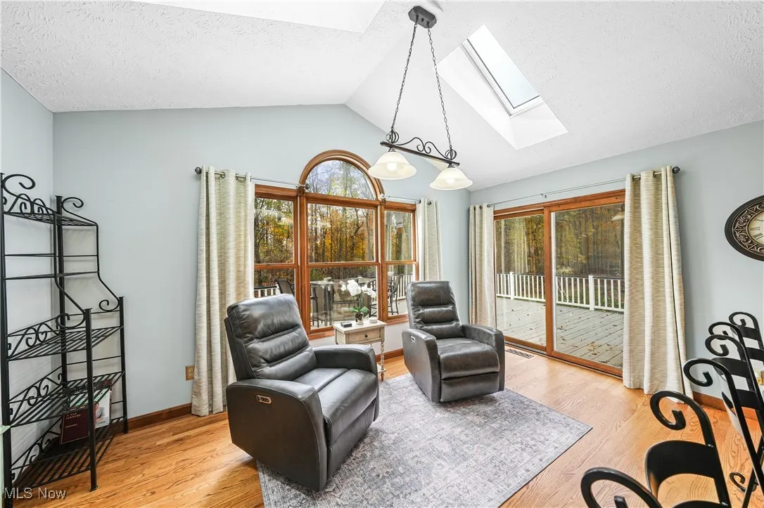 Living area with lofted ceiling, light wood-type flooring, a skylight, and a textured ceiling