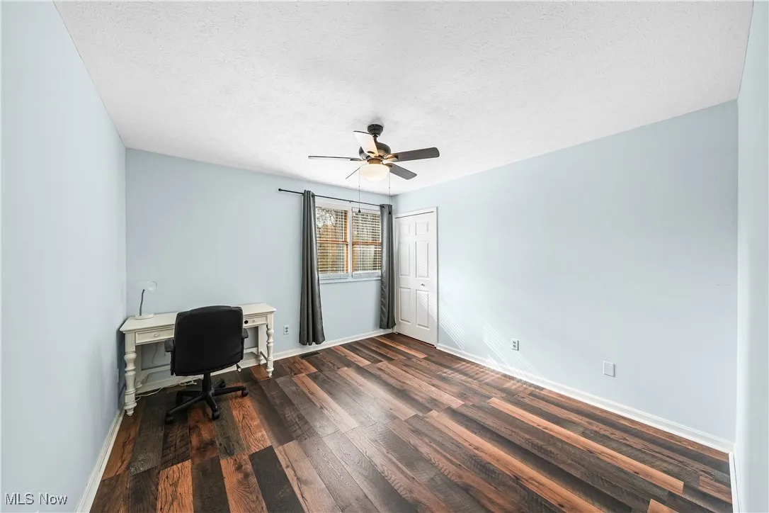 Home office with a textured ceiling, dark wood-style floors, and a ceiling fan