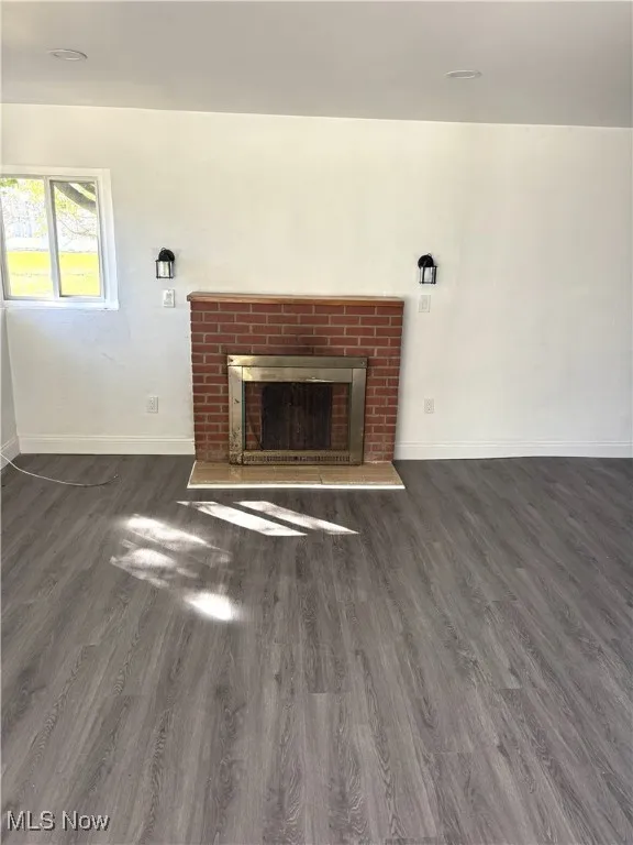 Unfurnished living room featuring a fireplace and dark wood-style floors