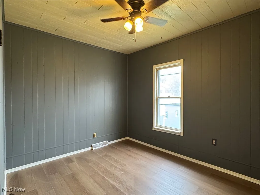 Spare room with wood walls, wood finished floors, a ceiling fan, and wooden ceiling