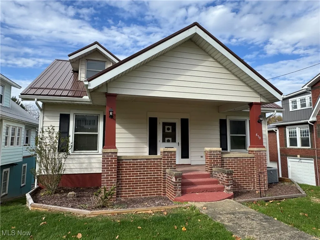Bungalow with covered porch, brick siding, and a front yard