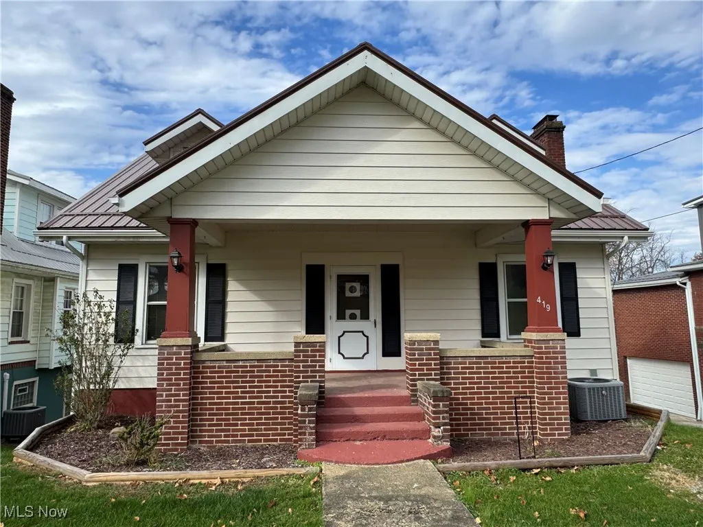 Bungalow-style home featuring covered porch, a chimney, and brick siding