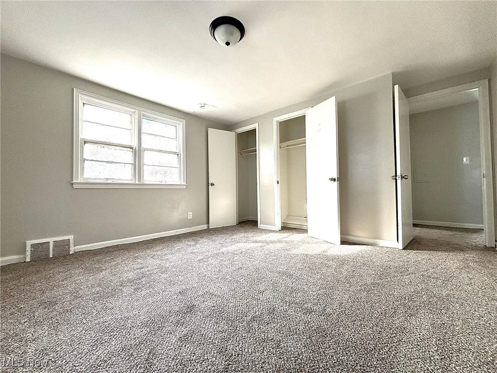 Unfurnished bedroom featuring carpet floors and two closets