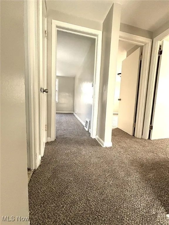 Corridor featuring carpet flooring and baseboards